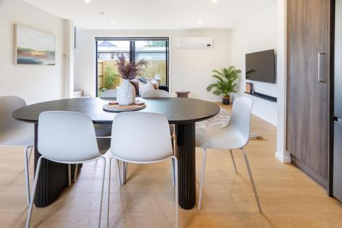a dining room with a table and white chairs at Modern Family-Friendly Home Near St Albans Park in Christchurch