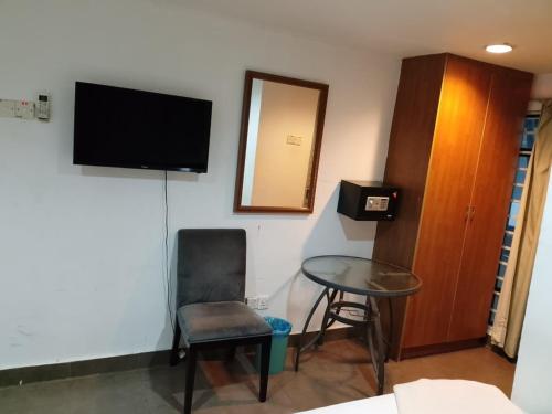 um quarto com uma mesa, uma cadeira e uma televisão em J Hotel Bukit Bintang em Kuala Lumpur