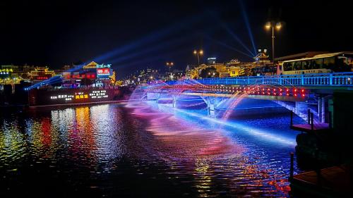 a bridge over a river at night with lights at GUI YUAN ZHEN PIN HOTEL,Approximately 3km away from the east gate of Zhangjiajie National Forest Park,Free Chinese western Breakfast,Free Self-Service Laundry , Attraction Tickets Serivce in advance,Free one-way shuttle service for 4 nights or more in Zhangjiajie