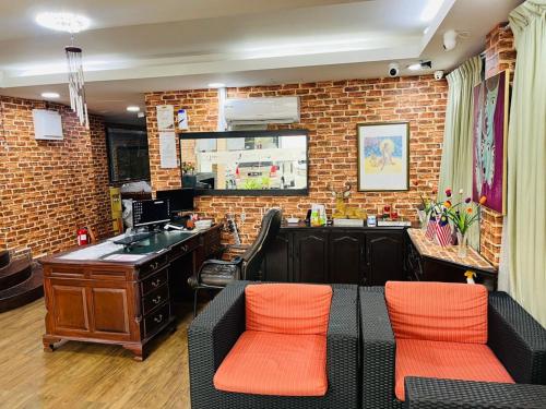 um bar com duas cadeiras laranja e uma parede de tijolos em J Hotel Bukit Bintang em Kuala Lumpur