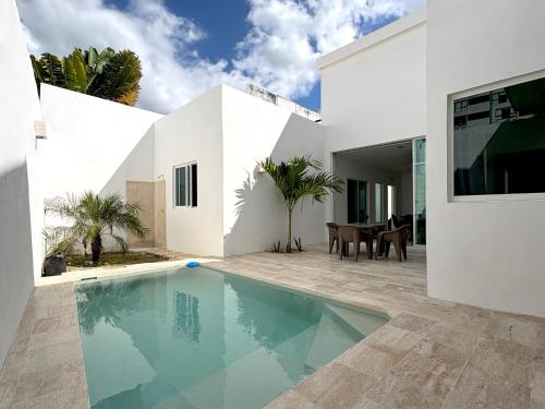 a white house with a swimming pool in front of it at Vica Mayan Guest House - By Aloja RV in Mérida
