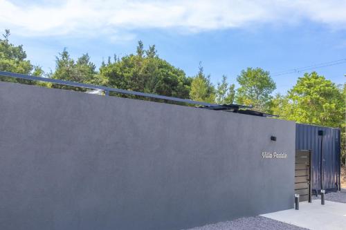 a gray wall with a gate and trees in the background at 淡路島 Villa Paddle - Self Check-In Only in Sumoto