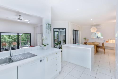 eine Küche mit weißen Arbeitsplatten und ein Esszimmer in der Unterkunft Stylish Family Retreat in Varsity by Housemark Escapes in Gold Coast