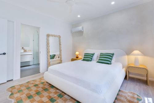 ein weißes Schlafzimmer mit einem weißen Bett und einem Spiegel in der Unterkunft Stylish Family Retreat in Varsity by Housemark Escapes in Gold Coast