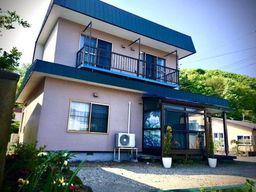 a large house with a balcony and a table at kitagunihouse noboribetsu in Noboribetsu