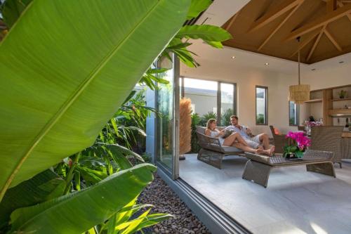a man and woman sitting on a couch in a living room at Boutique Resort 2BR Pool Villa Dalaa 2, Kamala Beach in Kamala Beach