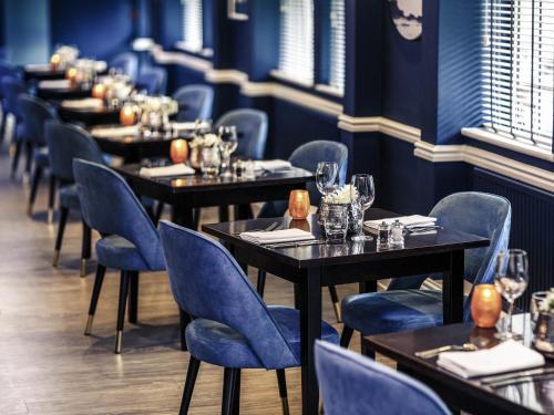 a row of tables in a restaurant with blue chairs at Mercure Swansea Hotel in Swansea