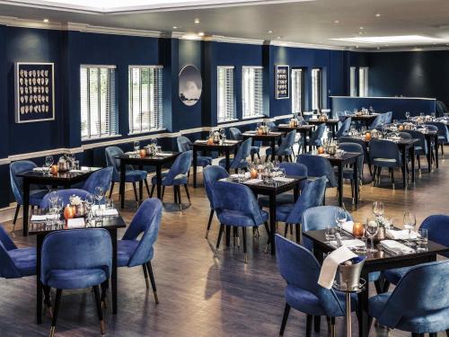 a dining room with tables and blue chairs at Mercure Swansea Hotel in Swansea