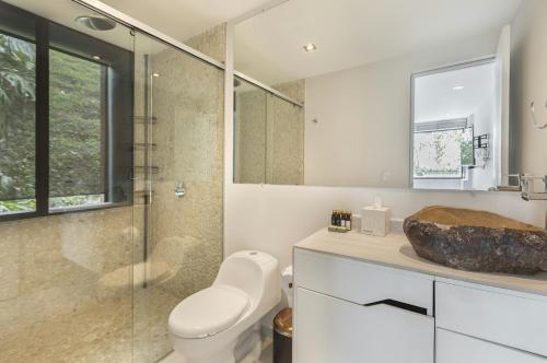 une salle de bain avec toilettes et douche en verre dans l'établissement Luxé Cabañas, à Guatapé