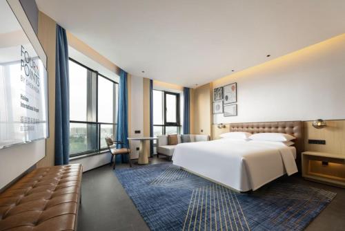 ein Schlafzimmer mit einem großen weißen Bett und einer Couch in der Unterkunft Four Points by Sheraton Haikou International Airport in Haikou
