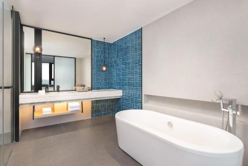 ein Badezimmer mit Badewanne, Waschbecken und Spiegel in der Unterkunft Four Points by Sheraton Haikou International Airport in Haikou