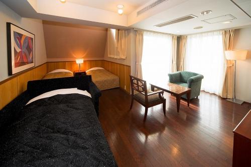 a bedroom with two beds and a desk and a chair at The Residential Suites Fukuoka in Fukuoka