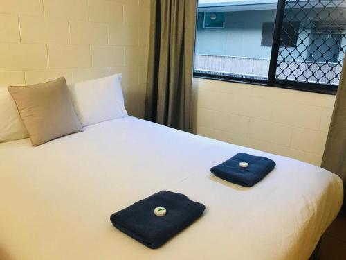 a bed with two blue pillows on top of it at Koala Beach Resort Cairns in Cairns