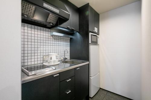 a kitchen with black cabinets and a sink at The Residential Suites Fukuoka in Fukuoka