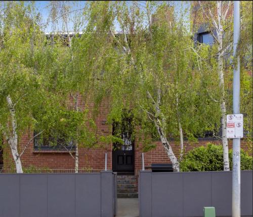 a brick building with a black door and trees at Renovated 1930's home in Sandy Bay