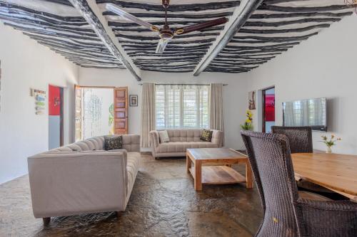 a living room with a ceiling fan and a table at Auregi Villas - 2 and 3 bedroom near Diani Beach in Diani Beach