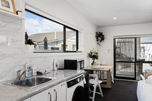 une cuisine avec un évier, une table et une fenêtre dans l'établissement Studio Unit 5 Mins Walk to CBD, à Gisborne