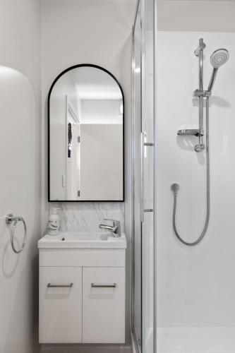 a white bathroom with a sink and a mirror at Studio Unit 5 Mins Walk to CBD in Gisborne