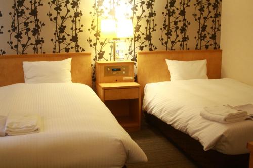 a hotel room with two beds with white sheets at Hotel Premium Green Sovereign in Sendai