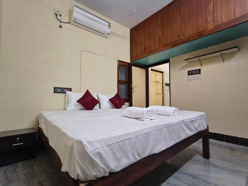 a bedroom with a bed with white sheets and red pillows at Entire 1bhk Home - Kumbha Nivas Homestay in Kumbakonam