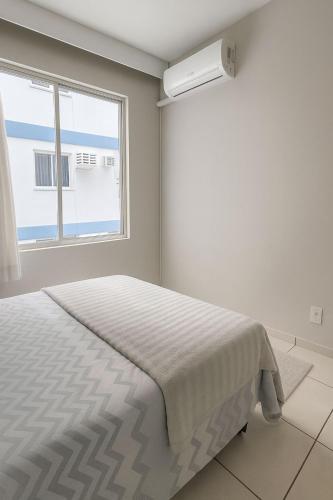 une chambre blanche avec un lit et une fenêtre dans l'établissement Ludgero BLU MARE BC, à Balneário Camboriú