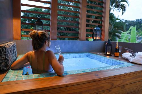 uma mulher sentada numa banheira de hidromassagem com um copo de vinho em Home Aguas da barra Ilhabela em Ilhabela