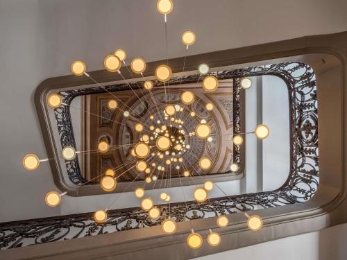 um espelho com um lustre na parede em La Cour des Consuls Hotel & Spa Toulouse - MGallery Collection em Toulouse