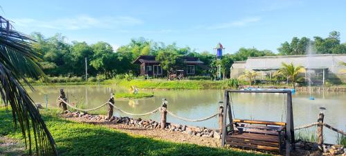 einen Teich mit einer Bank vor einem Haus in der Unterkunft ตาเล็ก ฟาร์มสเตย์ 