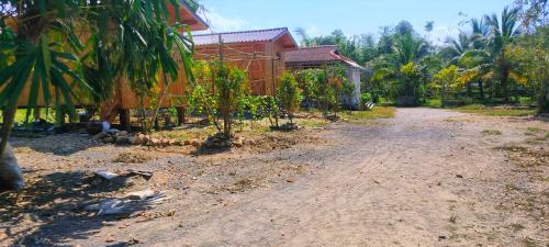 eine unbefestigte Straße vor einem Haus mit Bäumen in der Unterkunft ตาเล็ก ฟาร์มสเตย์ 