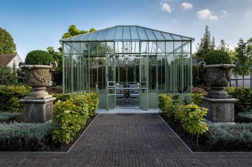 a glass greenhouse in a garden with two vases at B&B Vinedo in Zele