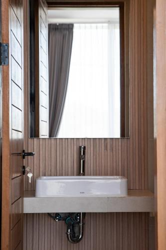 a bathroom sink with a mirror and a window at Swamis Villa in Tumbak Bayuh