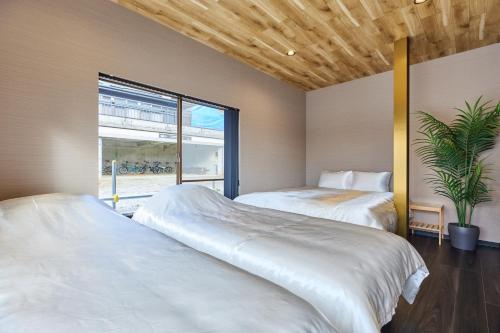 Dos camas en una habitación con ventana. en 富士山を見ながらサウナBBQ The No10 MtFuji Forest House, en Yamanakako