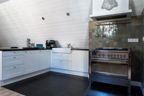 a kitchen with white cabinets and a stove at B&B Vinedo in Zele