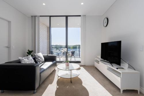 a living room with a couch and a tv at Cozy 2BR Apartment at Rosebery in Sydney