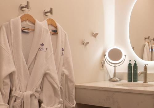 une salle de bain avec un peignoir suspendu à côté d'un lavabo dans l'établissement Violet Inn, Lounge & Spa, à Two Rivers