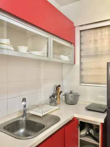 a kitchen with a sink and a red wall at Magallanes Residences Condominium 211&212B in Davao City