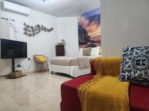 een slaapkamer met een bed, een bank en een tv bij Lofts #9 & #6 Surf EcoVilla Playa El Sunzal in El Sunzal