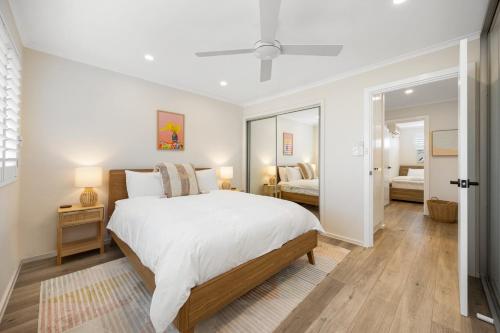 a white bedroom with a bed and a mirror at Hazy Shores Escape - Breezy Coastal Stay near Henley Square in Henley Beach