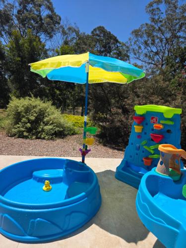 ein Sonnenschirm und zwei Spielgeräte in einem Garten in der Unterkunft Multi Award-Winning Holiday Home, Dido's Place in Kurrajong