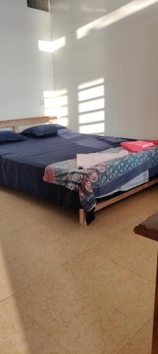 a bed with a blue comforter in a room at Om Ganesh Guest House Cliffside in Arambol