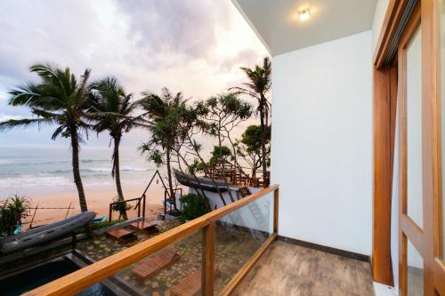 a balcony with a view of the beach and palm trees at LIYA BEACH- Luxury Boutique Hotel in Ahangama in Ahangama