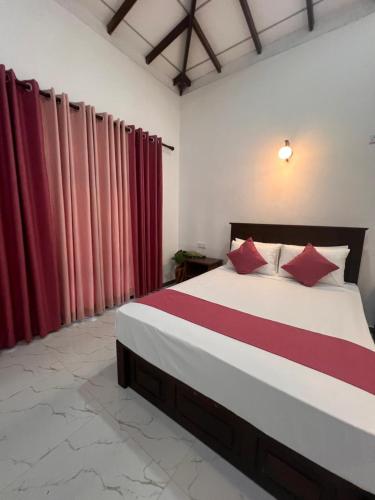 a bedroom with a large bed with red curtains at Mingu villa in Tangalle