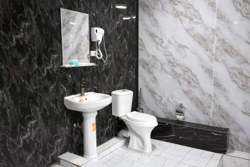 ein schwarz-weißes Badezimmer mit Toilette und Waschbecken in der Unterkunft Amor fati hotel Tashkent in Yakkasaray