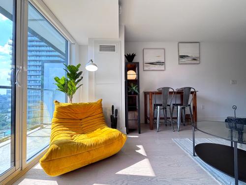 a yellow couch in a living room with a table at DT Cozy 1B1B with Den near UofT and Bay St in Toronto