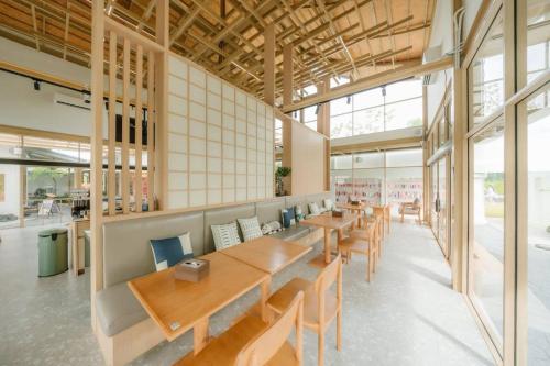 une cafétéria avec des tables et des chaises en bois et des fenêtres dans l'établissement Kiyomizu Onsen & Glamping Resort Saraburi, à Ban Nong Nak