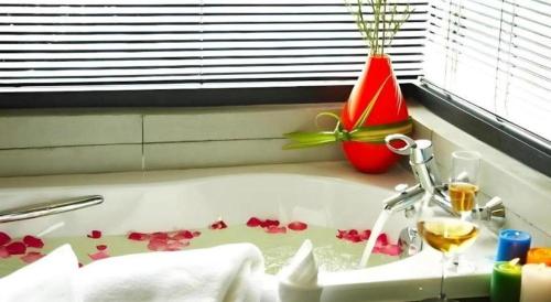 a bath tub filled with flowers and a glass of wine at The Sez Hotel Bangsaen in Ban Laem Thaen