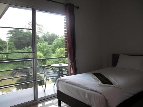 ein Schlafzimmer mit einem Bett und einem großen Fenster in der Unterkunft Sukthavorn Residence in Ban Pa Tung (7)