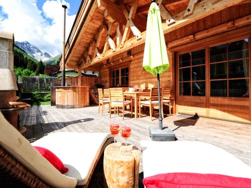 eine Holzhütte mit einem Tisch, Stühlen und einem Sonnenschirm in der Unterkunft Luxury Chalets Wiesenruh in Bichlbach