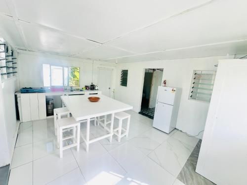 eine weiße Küche mit einem weißen Tisch und weißen Geräten in der Unterkunft Private Double Room - Airport Cottage in Fua‘amotu