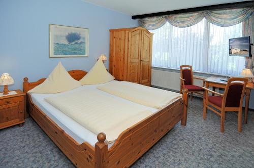 a bedroom with a large bed and a desk and a table at Hotel-Restaurant Faehr-Cafe in Niesgrau